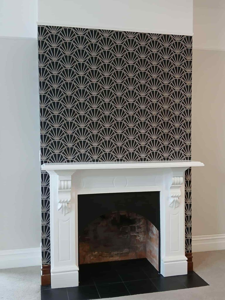 Art deco inspired wallpaper hung on this fireplace wall creates a sense of drama and elegance to this past project